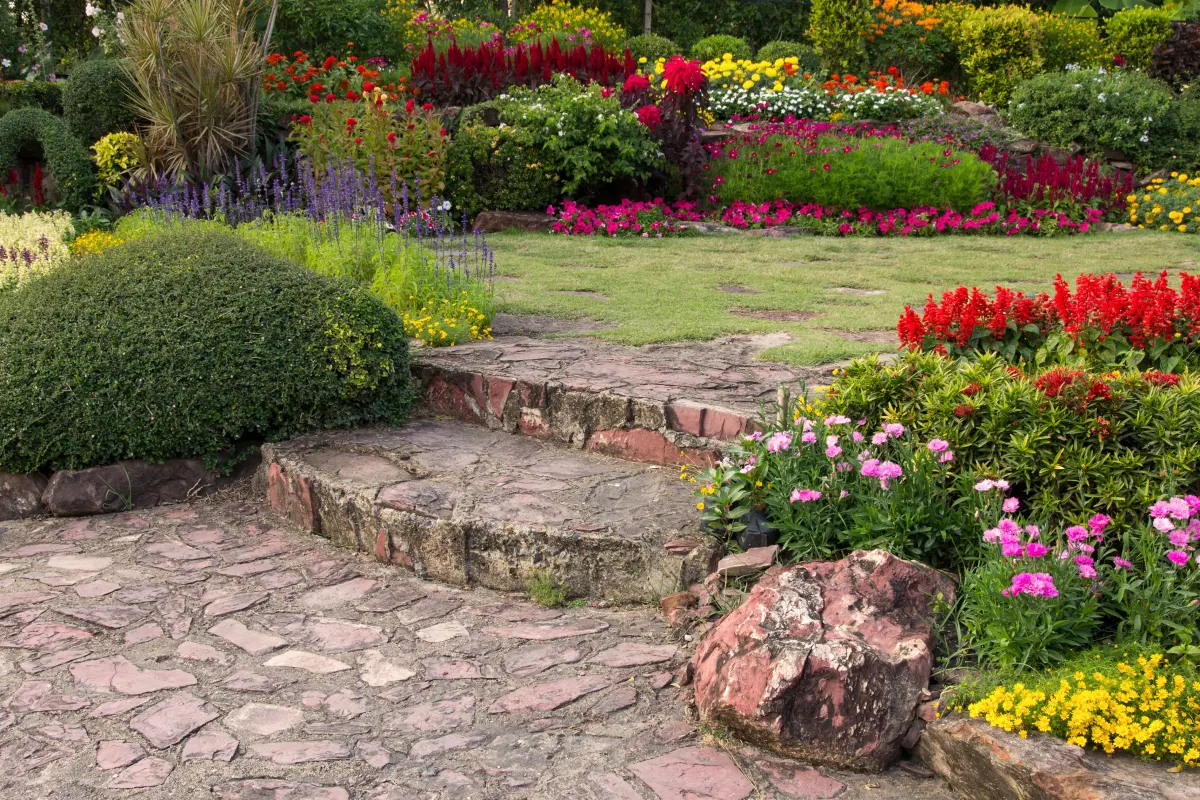 A beautifully designed patio with a fire pit and seating area, surrounded by lush green landscaping.